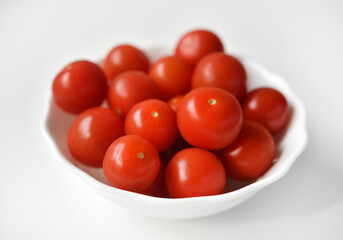 Wall Mural - Red fruits of small tomatoes in a glass plate. Juicy cherry tomatoes.