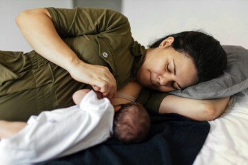 Brazilian mother and newborn baby. Mother breastfeeds her baby lying in bed