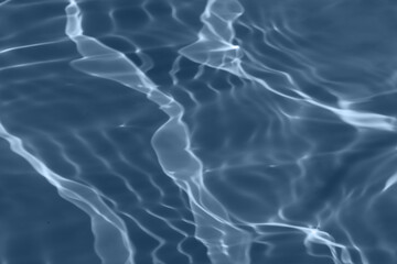 Blue water with ripples on the surface. Defocus blurred transparent blue colored clear calm water surface texture with splashes and bubbles. Water waves with shining pattern texture background.