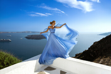 Wall Mural - Glamour, stylish elegant woman in long gown dress is posing near Skaros Rock in luxury resort in Santorini, Imerovigli. Female model in amazing long dress.