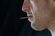Man with a toothpick in his mouth close up profile face, background selective focus, copy space people theme, story tel8ng.