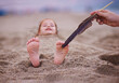 tickling happy baby's feet in a sand. family having fun on sandy beach. summer activity. coastal vacation