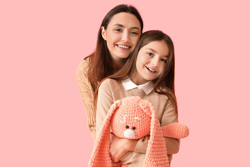 Poster - Little girl and her mother in warm sweaters with toy bunny on pink background