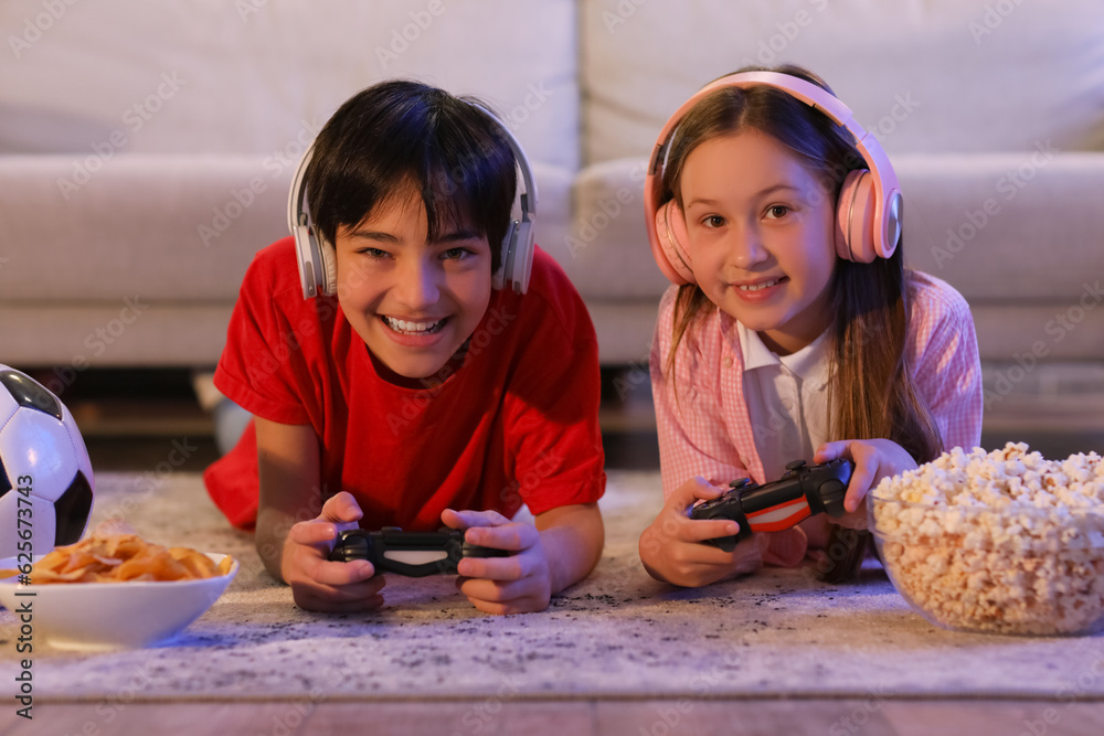 Little children playing video game at home in evening