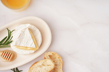 Plate with tasty Camembert cheese on light background