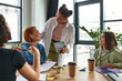 © LIGHTFIELD STUDIOS - happy african american woman talking to coach near multiethnic members of women interest club in friendly atmosphere with magazines and takeaway drinks, mutual support and understanding concept