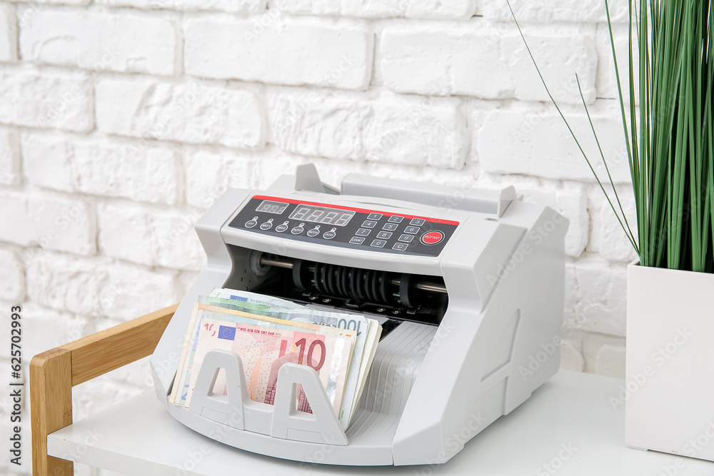 Cash counting machine with euro banknotes on shelf in office, closeup