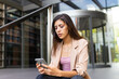 © ADDICTIVE STOCK - Businesswoman using smartphone near building