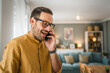 © Miljan Živković - One adult man with eyeglasses stand at home use mobile phone talk