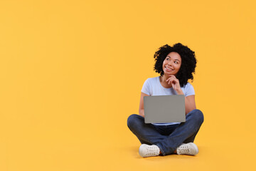 Happy young woman with laptop on yellow background. Space for text