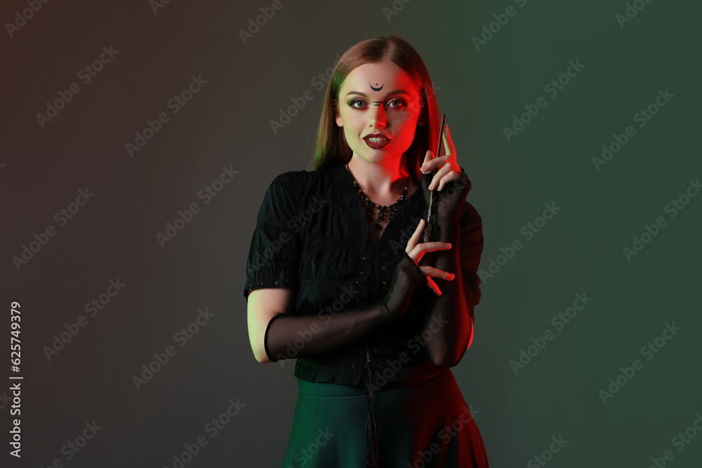 Beautiful young witch on dark background