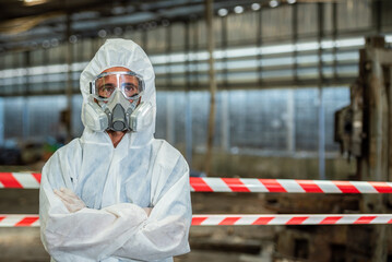 Male inspector  chemical PPE suit investigate chemical gas leak spill with safety face mask  in area closed barricade security tape. danger dirty area infected chemical leak spill cross stripe ribbon