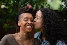 A Lesbian Couple Celebrate Their Engagement With Joyful And Romantic Photos In A Backyard. They Share A Kiss, Surrounded By The Rich Green Foliage Of Pines And Oaks. 