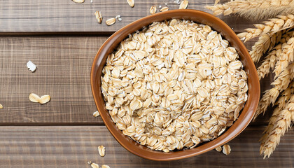 Sticker - oat flakes in bowl and ears on wooden table top view. Uncooked oatmeal