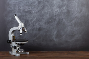 Back to school - microscope on the desk, Education concept. Blackboard background