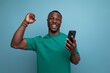 young handsome african man dressed in t-shirt uses smartphone for social media on isolated background with copy space