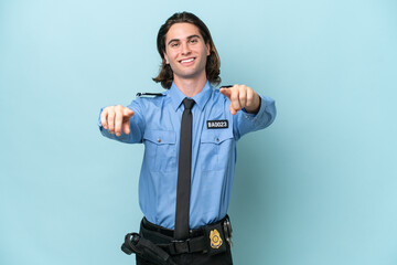 Wall Mural - Young police caucasian man isolated on blue background points finger at you while smiling