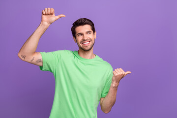 Photo of young man wear green t-shirt indicating fingers empty space advertisement shopping promo isolated on violet color background