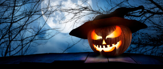 Wall Mural - the spooky haunted evil glowing eyes of jack o' lanterns, halloween pumpkin, on the right of a woode
