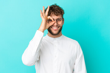 Wall Mural - Young handsome caucasian man isolated on blue background With glasses with happy expression