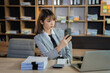 © NINENII - businesswoman sits in a office working on smartphone play social media and enjoys a coffee.