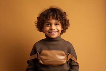 Wall Mural - happy african american child in brown sweater with bag isolated on beige