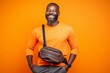 © igolaizola - happy african american man with backpack on orange background, travel concept