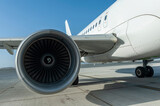 Fototapeta  - Unidentified plane engine and fuselage parked on airport runway with blue sky and copy space. Travel and transportation industry technology 