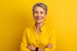 © igolaizola - Portrait of smiling mature woman in yellow shirt on yellow background.