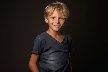 Wall Mural - Portrait of a cute little boy with blond hair on a black background