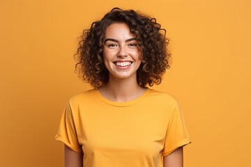 Wall Mural - Portrait of a beautiful young woman smiling at camera isolated over yellow background