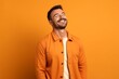 © igolaizola - happy young man laughing and looking away on orange background, side view