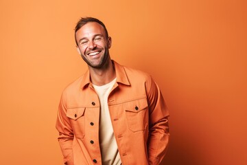 Poster - Portrait of a smiling casual man standing over orange background, looking at camera