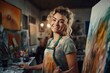 Portrait of a smiling female artist painting on canvas in art studio