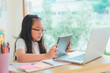© kongga studio - Asian school girl doing homework at laptop raising hand pointing finger . The girl does his homework. Home schooling.