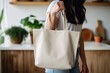 A woman is carrying a canvas tote bag. The tote bag mockup is white with minimalist background