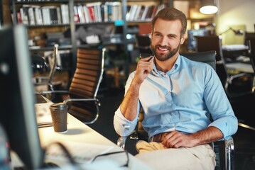 Wall Mural - I love my work. Young bearded businessman in formal wear thinking about something and smiling while sitting in modern office