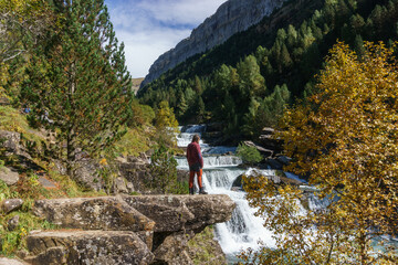 Wall Mural - waterfall with male hiker in Ordesa valley during autumn in the pyrenees mountains, Ordesa and Monte Perdido National Park, Huesca, Aragon, Spain