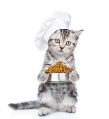 Wall Mural - Funny tabby kitten weaing chef's hat holds bowl of dry food. isolated on white background