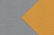 Texture of dark gray paper background, half two colors with orange arrow, macro. Structure of craft grey cardboard.