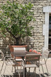 Cozy courtyard of a French house, a table with chairs on an open terrace. Outdoor cafe in summer in Provence, France, Europe. Ancient stone building.