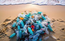 Discarded Plastic Bottles And Other Litter Collected From A Beach, Surrounded By Sand And Ocean Waves, Advocating For The Importance Of Beach Cleanup And Waste Reduction