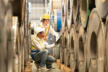 two professional engineer,worker,technician use clipboard discuss work, walk in steel metal manufacture factory plant industry. Black African American man and woman wear hard hat check quality machine