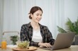© Charlie's - Happy beautiful Asian woman using computer laptop for work online at living room
