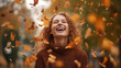 Joyful young woman rejoices in autumn, tossing fallen yellow leaves in the park.