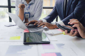 Wall Mural - Business documents on office table with smart phone and calculator digital tablet and graph business with social network diagram and two colleagues discussing data working in office