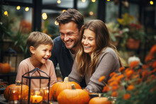 Happy Smiling Family Spending Time Together, Sitting At The Table Decorated With Autumn Pumpkins, Outdoors In The Backyard
