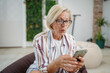 © Miljan Živković - Mature woman use mobile smart phone play video games sit indoor