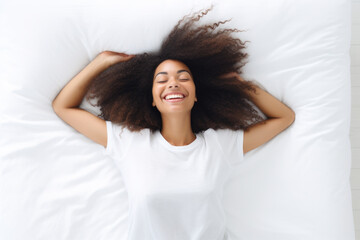 Top view from above smiling young woman stretching, lying in comfortable bed after awakening, happy positive young female wearing pajama resting on soft pillows under warm blanket, enjoying morning