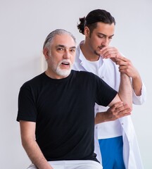 Wall Mural - Old injured man visiting young doctor